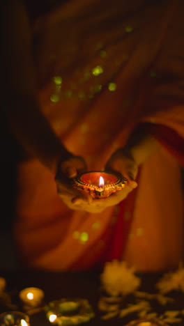 Vertical-Video-Close-Up-Of-Woman-Celebrating-Festival-Of-Diwali-Holding-Lit-Diya-Oil-Lamp-1